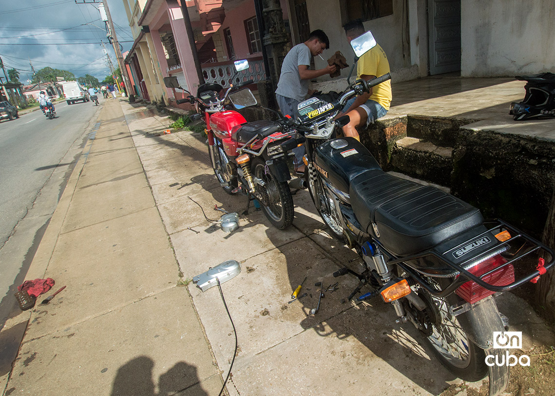 Hombres reparan motos en la calle, en San José de las Lajas. Foto: Otmaro Rodríguez.