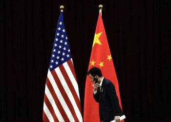 Un funcionario chino camina junto a las banderas nacionales de EE.UU. y China, en una fotografía de archivo. Foto: Andy Wong / EFE / EPA / Archivo.