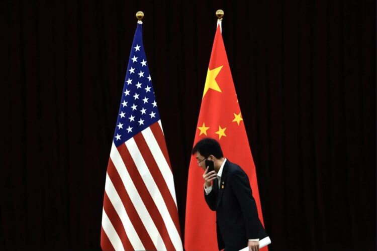 Un funcionario chino camina junto a las banderas nacionales de EE.UU. y China, en una fotografía de archivo. Foto: Andy Wong / EFE / EPA / Archivo.