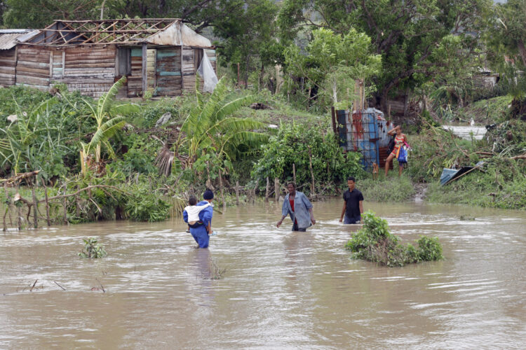 Personas cruzan un río crecido en el municipio de Guamá en Santiago de Cuba, tras el paso del potente huracán Melissa. Foto: Ernesto Mastrascusa / EFE.