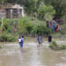 Personas cruzan un río crecido en el municipio de Guamá en Santiago de Cuba, tras el paso del potente huracán Melissa. Foto: Ernesto Mastrascusa / EFE.