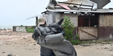 Un hombre carga una lona para cubrir el techo de una casa antes del paso del huracán Melissa, en la playa pesquera de Hellshire, en Portmore, Jamaica. Foto: Rudolph Brown/EFE.
