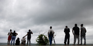 25/10/2025.- Personas observan las labores de búsqueda de un adolescente de 13 años que desapareció en aguas del Caribe, durante el paso del huracán Melissa este sábado, en Santo Domingo (República Dominicana). Foto: EFE/ Orlando Barría.