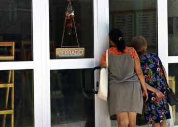 Personas observan el interior de una local cerrado por falta de electricidad, durante un apagón en La Habana. Foto: Ernesto Mastrascusa / EFE.