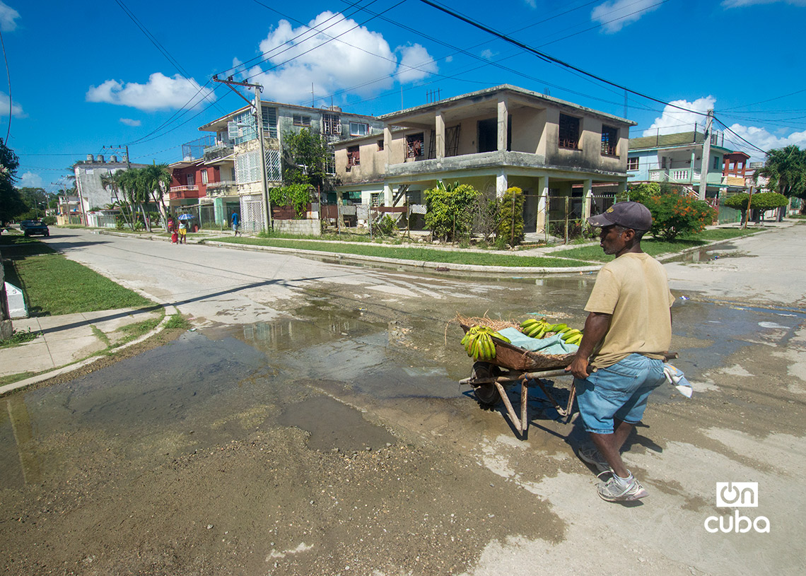 Vendedor ambulante, cruza el agua acumulada en una calle del reparto Casino Deportivo, en La Habana. Foto: Otmaro Rodríguez.