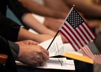 Un nuevo ciudadano estadounidense sostiene una pequeña bandera estadounidense sobre un papel con la letra del himno nacional durante una ceremonia de naturalización en la Biblioteca Central de Los Ángeles, en Los Ángeles, California, EE.UU. Foto: ETIENNE LAURENT/EFE/EPA.
