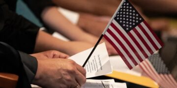 Un nuevo ciudadano estadounidense sostiene una pequeña bandera estadounidense sobre un papel con la letra del himno nacional durante una ceremonia de naturalización en la Biblioteca Central de Los Ángeles, en Los Ángeles, California, EE.UU. Foto: ETIENNE LAURENT/EFE/EPA.