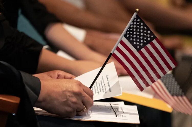 Un nuevo ciudadano estadounidense sostiene una pequeña bandera estadounidense sobre un papel con la letra del himno nacional durante una ceremonia de naturalización en la Biblioteca Central de Los Ángeles, en Los Ángeles, California, EE.UU. Foto: ETIENNE LAURENT/EFE/EPA.