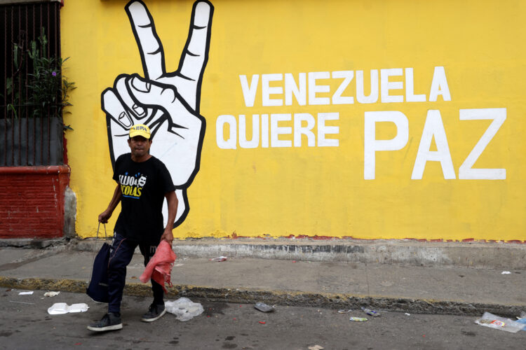 Un hombre camina frente a un mural, en Caracas. Foto:  Ronald Peña R/EFE.