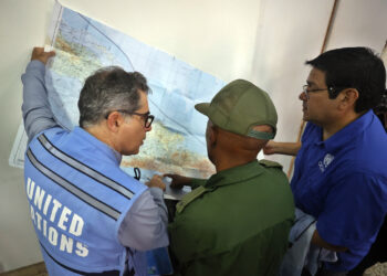 El representante de la ONU en Cuba, Francisco Pichon (i), intercambia con otras autoridades y observa un mapa para realizar un sobrevuelo por las zonas afectadas por el huracán Melissa en el oriente de Cuba. Foto: Ernesto Mastrascusa / EFE.