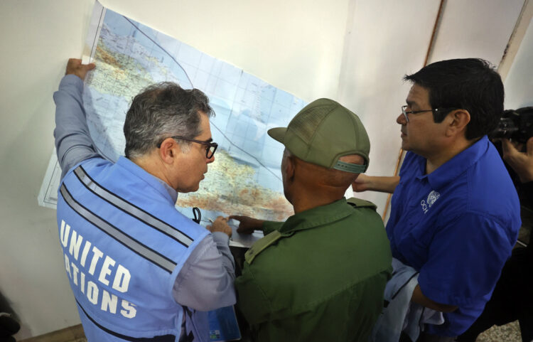 El representante de la ONU en Cuba, Francisco Pichon (i), intercambia con otras autoridades y observa un mapa para realizar un sobrevuelo por las zonas afectadas por el huracán Melissa en el oriente de Cuba. Foto: Ernesto Mastrascusa / EFE.