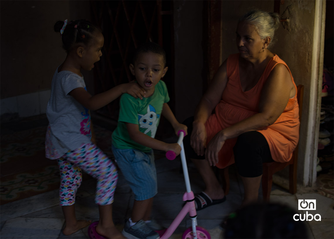 Unos niños juegan junto a su abuela durante un apagón por la caída del Sistema Eléctrico Nacional. Foto: Otmaro Rodríguez.
