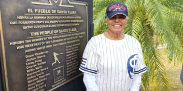 Maureen Taylor Hicks posa frente a la tarja de bronce que recuerda a los jugadores afroestadounidenses del equipo Los Leopardos, de San Clara. Foto cortesía de MTH.