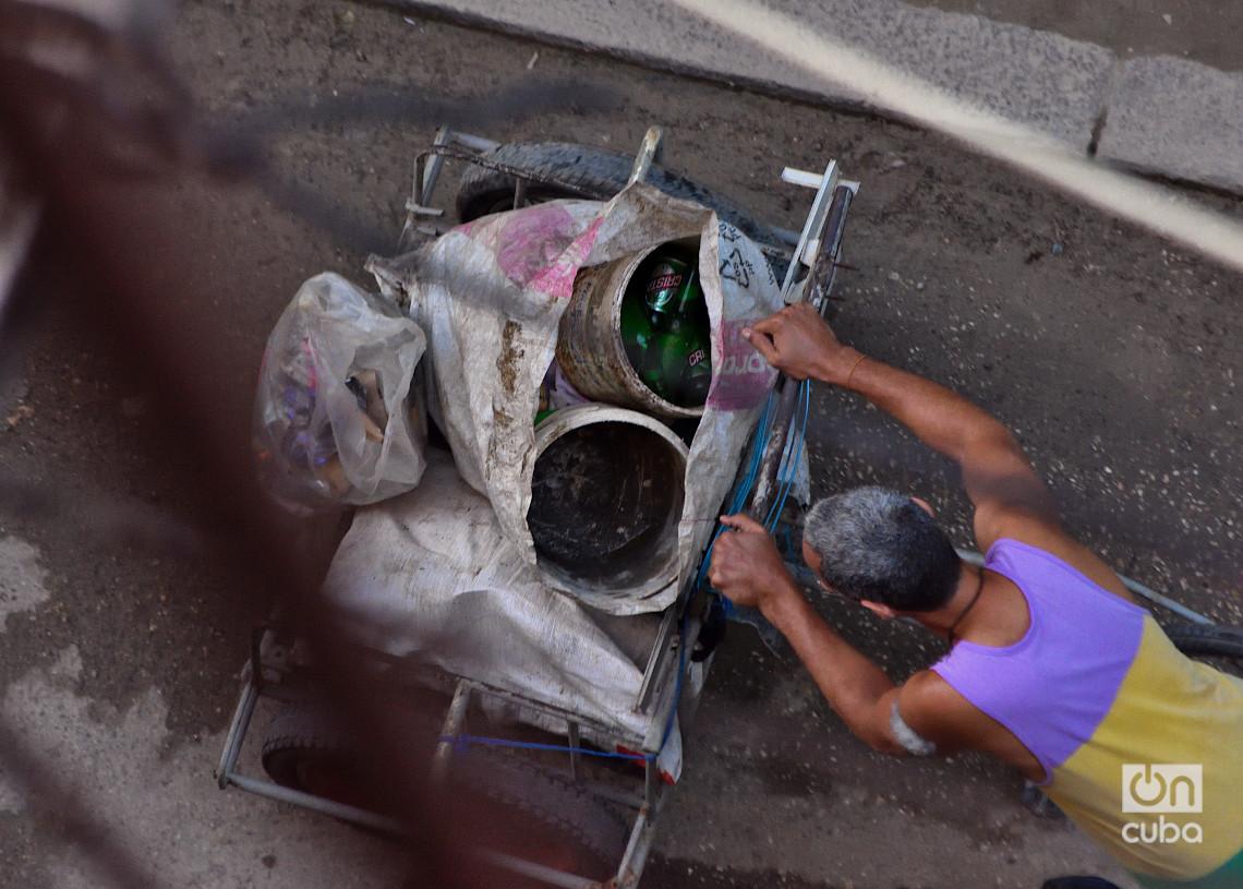Un hombre empuja una carretilla con botellas y otras cosas rescatadas de la basura. Foto: Otmaro Rodríguez.