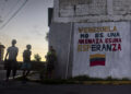 Niños y adolescentes junto a un mural con un mensaje en apoyo al Gobierno de Venezuela en Caracas Foto: Miguel Gutiérrez / EFE.