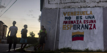 Niños y adolescentes junto a un mural con un mensaje en apoyo al Gobierno de Venezuela en Caracas Foto: Miguel Gutiérrez / EFE.