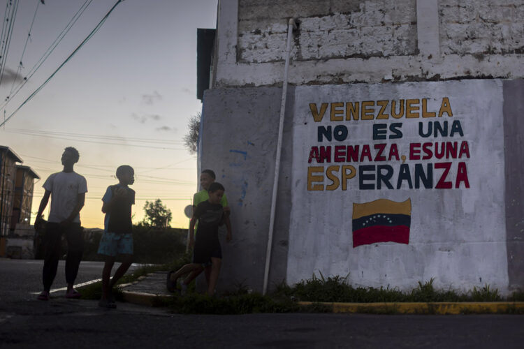 Niños y adolescentes junto a un mural con un mensaje en apoyo al Gobierno de Venezuela en Caracas Foto: Miguel Gutiérrez / EFE.