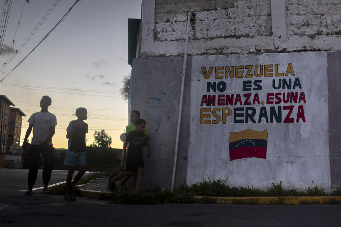 Niños y adolescentes junto a un mural con un mensaje en apoyo al Gobierno de Venezuela en Caracas Foto: Miguel Gutiérrez / EFE.