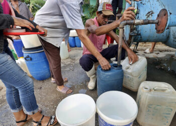 Varias personas hacen fila para abastecerse de agua en Cauto Cristo, Granma, tras el paso del huracán Melissa. Foto: Ernesto Mastrascusa / EFE.