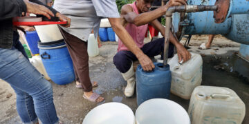 Varias personas hacen fila para abastecerse de agua en Cauto Cristo, Granma, tras el paso del huracán Melissa. Foto: Ernesto Mastrascusa / EFE.