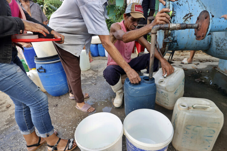 Varias personas hacen fila para abastecerse de agua en Cauto Cristo, Granma, tras el paso del huracán Melissa. Foto: Ernesto Mastrascusa / EFE.