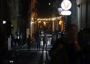 Personas caminan por una calle adornada con luces de Navidad en La Habana. Foto: Ernesto Mastrascusa / EFE.