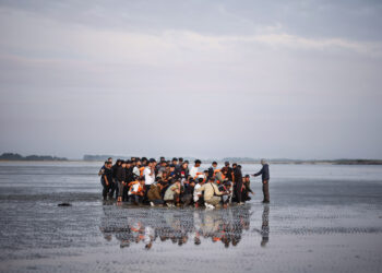 Migrantes esperan en una playa para abordar una lancha inflable y cruzar el Canal de la Mancha, en Gravelines, norte de Francia. Foto: Yoan Valat/EFE/Archivo.