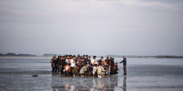 Migrantes esperan en una playa para abordar una lancha inflable y cruzar el Canal de la Mancha, en Gravelines, norte de Francia. Foto: Yoan Valat/EFE/Archivo.