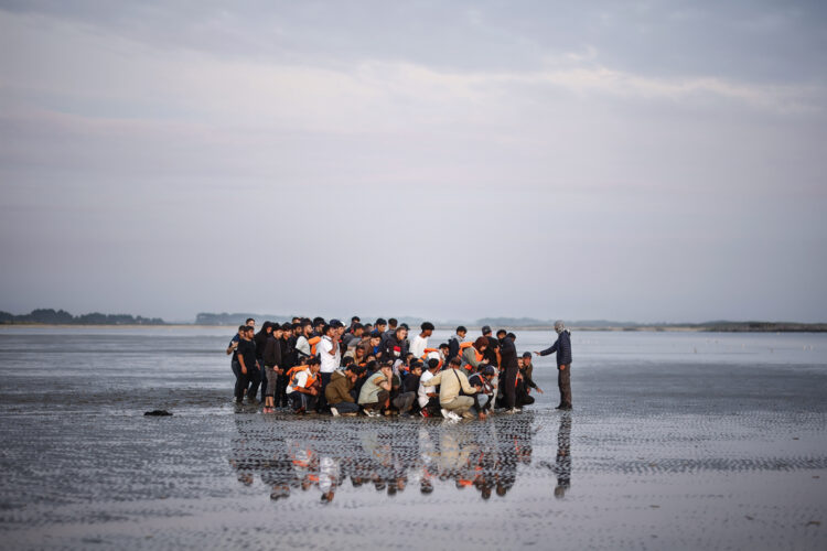 Migrantes esperan en una playa para abordar una lancha inflable y cruzar el Canal de la Mancha, en Gravelines, norte de Francia. Foto: Yoan Valat/EFE/Archivo.