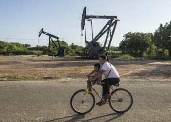 Una mujer conduce junto a un niño una bicicleta frente a balancines petroleros, en Cabimas, Venezuela. El mandatario brasileño dijo no comprender las razones de la actual tensión entre Washington y Caracas y mencionó como posibles factores el petróleo, los minerales estratégicos. Foto: Henry Chirinos/ EFE.