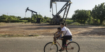 Una mujer conduce junto a un niño una bicicleta frente a balancines petroleros, en Cabimas, Venezuela. El mandatario brasileño dijo no comprender las razones de la actual tensión entre Washington y Caracas y mencionó como posibles factores el petróleo, los minerales estratégicos. Foto: Henry Chirinos/ EFE.
