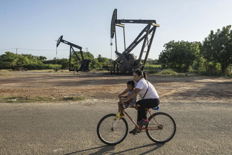 Una mujer conduce junto a un niño una bicicleta frente a balancines petroleros, en Cabimas, Venezuela. El mandatario brasileño dijo no comprender las razones de la actual tensión entre Washington y Caracas y mencionó como posibles factores el petróleo, los minerales estratégicos. Foto: Henry Chirinos/ EFE.