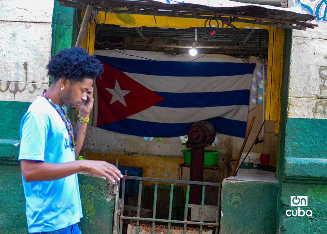 A young man walks past a Cuban flag inside a store in Havana. Photo: Otmaro Rodríguez.