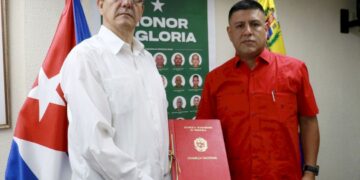 El primer vicepresidente de la Asamblea Nacional de Venezuela, Pedro Infante, (der) entrega al embajador de Cuba, Jorge Luis Mayo, un acuerdo que declara “héroes y mártires” a los 32 militares cubanos muertos en los ataques de EE.UU. Foto: Asamblea Nacional de Venezuela / Facebook.