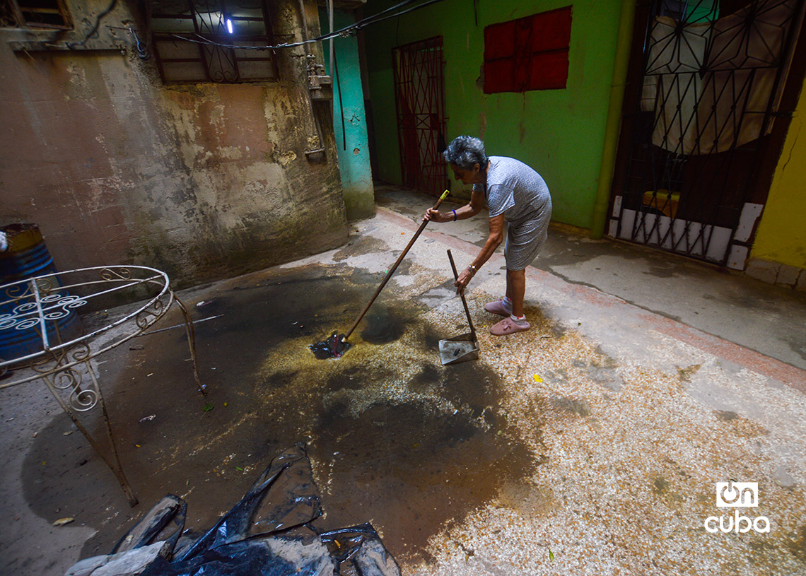 An elderly woman cleans the interior patio of a building in Havana. Photo: Otmaro Rodríguez.