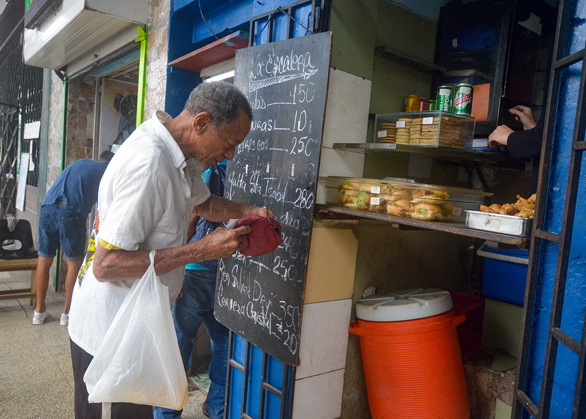 A man looks for money to buy food in a private cafeteria in Havana. Photo: Otmaro Rodríguez.
