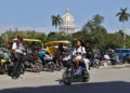 Personas pasean en moto cerca del Capitolio de La Habana este jueves, en La Habana. Foto: Ernesto Mastrascusa/EFE.