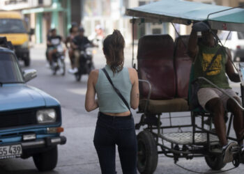 Fotografía de archivo del 11 de julio de 2024 que muestra a una mujer esperando un taxi en La Habana. Foto:  Yander Zamora/ EFE/ARCHIVO.