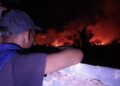 Un hombre observa desde un balcón el incendio desatado en torno al reparto Armando Mestre, en la zona conocida como El Naranjal, en Matanzas, en la noche del 13 de enero de 2026. Foto: Periódico Girón / Facebook.