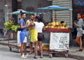 Mujeres y hombres en los alrededores de un puesto de venta callejera de coco, en una calle de La Habana. Foto: Ernesto Mastrascusa / EFE.