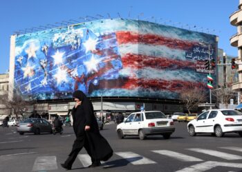 Una mujer iraní con velo camina cerca de una enorme valla publicitaria contra Estados Unidos colgada en la plaza Enqelab de Teherán, Irán, el 31 de enero de 2026. Foto: EFE/EPA/ABEDIN TAHERKENAREH