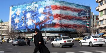Una mujer iraní con velo camina cerca de una enorme valla publicitaria contra Estados Unidos colgada en la plaza Enqelab de Teherán, Irán, el 31 de enero de 2026. Foto: EFE/EPA/ABEDIN TAHERKENAREH