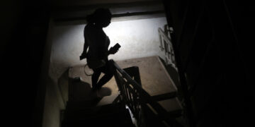Una persona baja escaleras mientras alumbra con un teléfono durante un apagón. Foto: EFE/ Ernesto Mastrascusa.