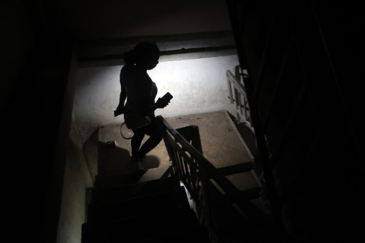 Una persona baja escaleras mientras alumbra con un teléfono durante un apagón. Foto: EFE/ Ernesto Mastrascusa.