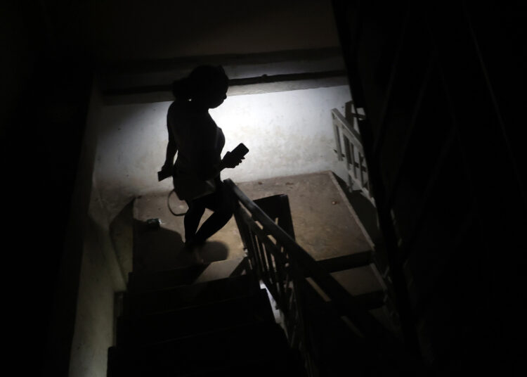 Una persona baja escaleras mientras alumbra con un teléfono durante un apagón. Foto: EFE/ Ernesto Mastrascusa.