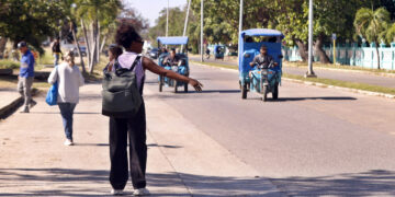 Una mujer agita su brazo para tomar un vehículo eléctrico este lunes, en La Habana. Foto:  Ernesto Mastrascusa/EFE.
