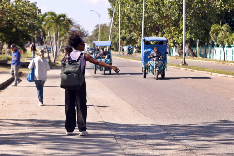 Una mujer agita su brazo para tomar un vehículo eléctrico este lunes, en La Habana. Foto:  Ernesto Mastrascusa/EFE.