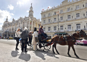Turistas montando en un coche alado por un caballo en La Habana. Foto:  Ernesto Mastrascusa/EFE.