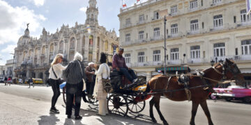 Turistas montando en un coche alado por un caballo en La Habana. Foto:  Ernesto Mastrascusa/EFE.