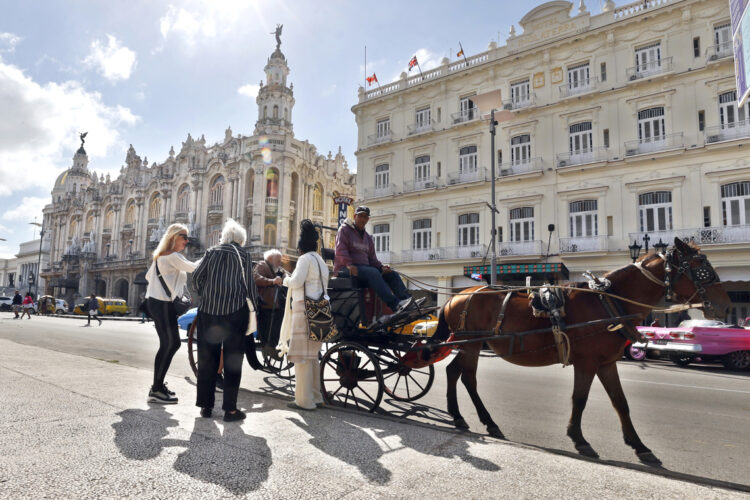 Turistas montando en un coche alado por un caballo en La Habana. Foto:  Ernesto Mastrascusa/EFE.